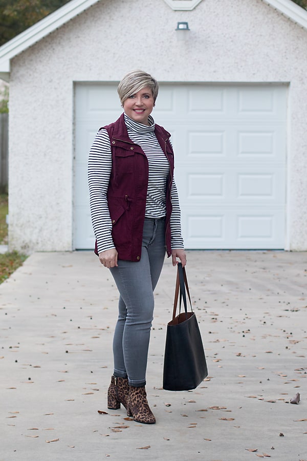grey jeans and a burgundy utility vest create a great fall outfit